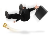 Businessman slipping and falling from a banana peel on a white background